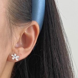 Elegant S925 silver flower stud earrings with blue gemstone accents on model's ear