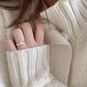 Close-up of elegant silver pearl ring on hand with soft white knit sweater background