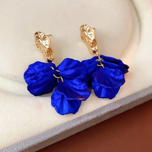 Close-up of vintage gold earrings with dark blue petal tassels on a jewelry pad