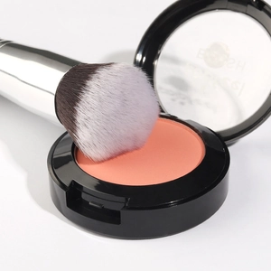 Round head powder brush with soft fiber bristles and matte peach blush in black case