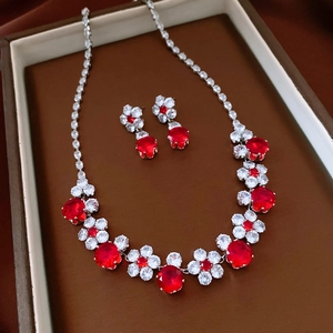 Detailed view of luxury silver necklace and red zircon flower earrings in a gift box