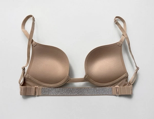 Detail of nude push-up bra featuring shimmering silver rhinestone back straps on grey