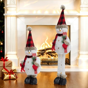 Detailed view of plush snowman dolls with red plaid hats and skis by a festive fireplace