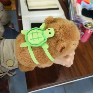 Detail shot of a plush Capybara snap bracelet with a turtle backpack worn on a wrist