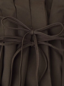 Detailed close-up of dark brown pleated fabric with an elegant double-layered bow tie element