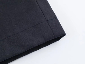 Detailed macro view of the double-needle stitching on navy blue woven coat cuffs