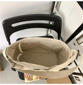 Top view of the spacious inner compartment of the cream canvas tote bag on a chair