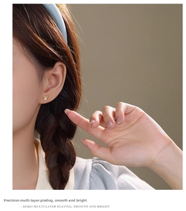 Detail of gold bow earrings with zircon on model showing the layered plating finish