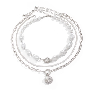 Three-layer silver necklace with baroque pearls and a textured coin pendant on white background