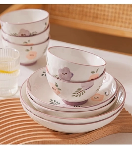 Detail of floral ceramic bowls and plates set with purple hand-painted flower patterns