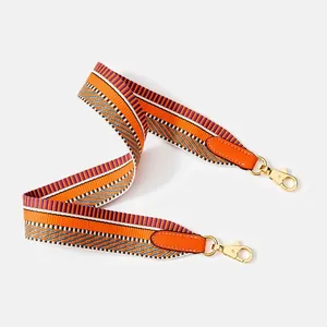 Detail of colorful striped woven strap with orange leather and gold swivel hooks