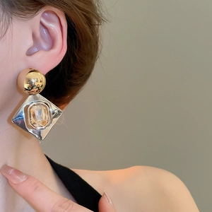 Gros plan de boucles d'oreilles losanges avec pierre ambre sur une oreille
