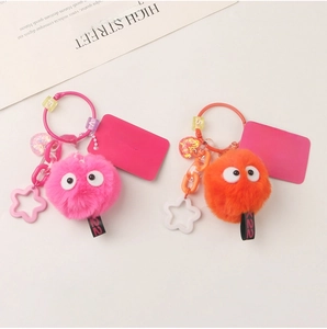 Detail of pink and orange plush keychains with star charms and cute letter beads