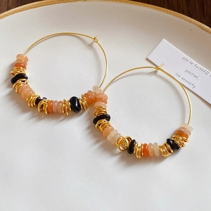 Close-up of vintage gold hoop earrings with agate stone beads on a white ceramic tray