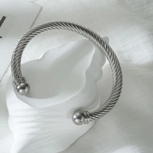 Silver stainless steel twisted cable open cuff bracelet with spherical ends on white shell