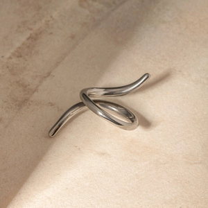 Modern twisted silver stainless steel ring displayed on a natural stone background