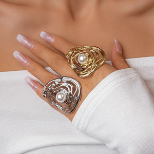 Detail shot of irregular hollow gold and silver rings with large pearl inlay on hand