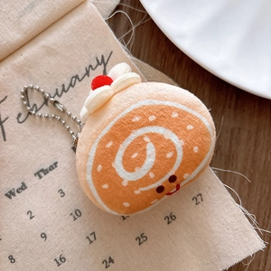 Close-up of a soft plush Swiss roll cake keychain with a cute embroidered smiley face