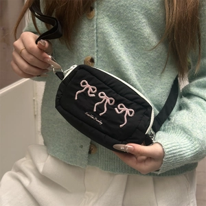 Detail der schwarzen Umhängetasche mit rosa Schleifenstickerei und Sophie Friday Logo