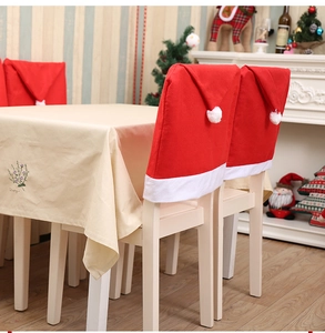 Detail of red Santa hat chair covers with white plush trim on holiday dining table