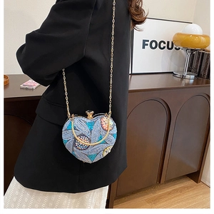 Detail of heart-shaped evening bag with floral embroidery and gold chain strap