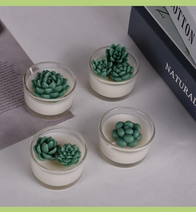 Top-down view of four realistic succulent-shaped scented candles in clear glass jars