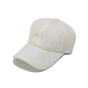Dettaglio cappello baseball in pizzo bianco con ricami floreali e trama traspirante