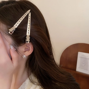 Détail d'une pince à cheveux minimaliste en métal argenté ajouré portée sur les cheveux