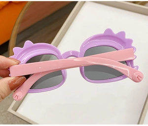 Close-up of cute purple and pink dinosaur sunglasses for kids with cartoon design