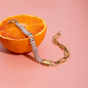 Macro detail of 18K gold stainless steel bracelet with rectangular zircons on an orange