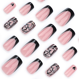 Pink French fake nails with black heart patterns and small rhinestones on white background