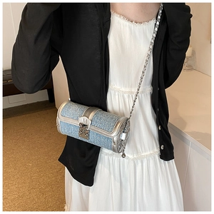 Model wearing a blue tweed cylinder crossbody bag with silver leather trim and chain strap