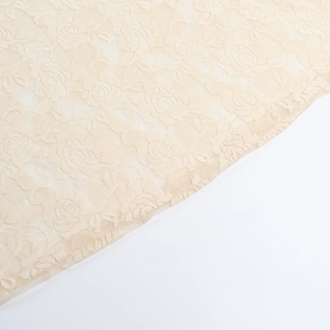 Detailed close-up of beige floral lace fabric with delicate rose embroidery patterns