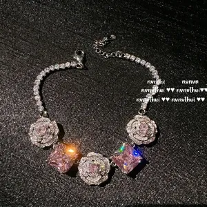 Close-up of pink square zircons and pavé-set rose flowers on a silver vintage necklace
