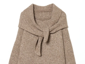 Close-up of knit fabric texture on brown sweater with decorative neckline tie detail