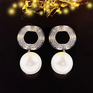 Detailed view of silver hoop earrings with shimmering zircons and large white pearls