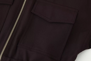 Close-up of high-quality silver metal zipper and flap pocket on dark twill jacket