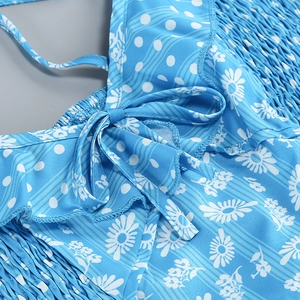 Close-up of floral light blue dress featuring ruffles, bow tie, and smocked waist texture