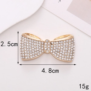 Macro detail of a 4.8cm zinc alloy bow charm with white rhinestones on golden metal base