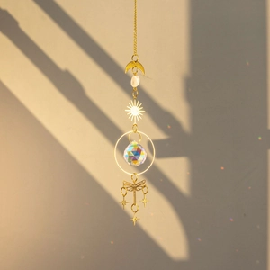 Golden brass dragonfly suncatcher with raw crystal ball casting rainbow light on window