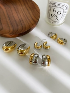 Close-up of mixed metal gold and silver hoop earrings on a minimalist white surface