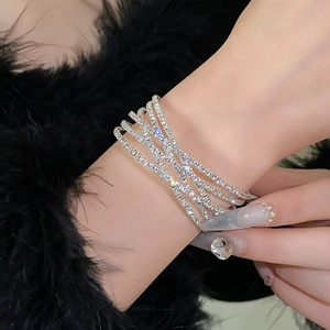 Detail van meerlaagse zilveren kruisarmband met glanzende zirkonia kristallen voor dames