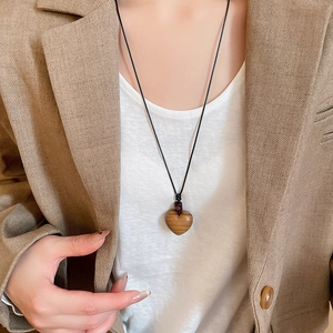 Detail of wooden heart pendant with natural grain on a wax cord necklace worn by model