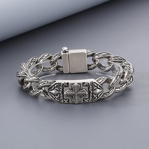 Detailed view of vintage silver cross bracelet with gothic rose patterns and heavy metal links