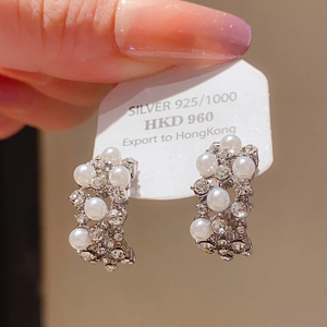 Detail of silver bow earrings with micro-set pearls and shimmering cubic zirconia stones