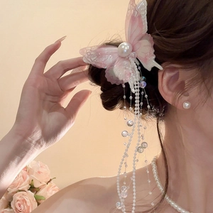 Detailed close-up of a pink mesh butterfly hair clip with long pearl tassels on hair