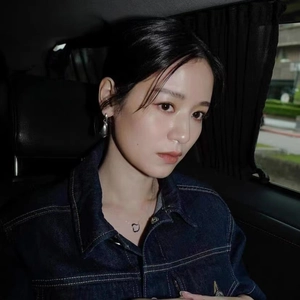 Close-up of silver teardrop earrings and heart pendant necklace on a denim jacket model