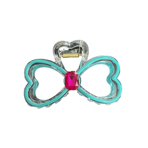 Teal bow-shaped hair claw clip with pink gemstone and gold metal spring on white background