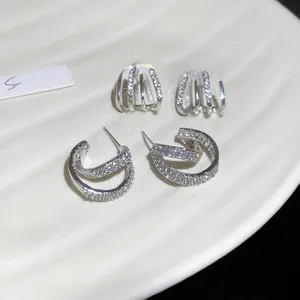 Macro shot of double-layered silver C-shape earrings with sparkling cubic zirconia inlay