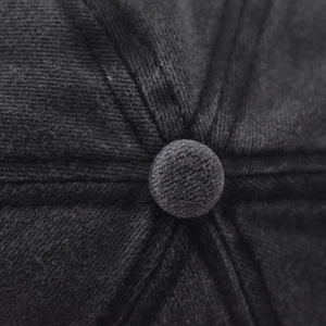 Macro shot of the central top button on a dark grey washed cotton baseball cap with twill texture